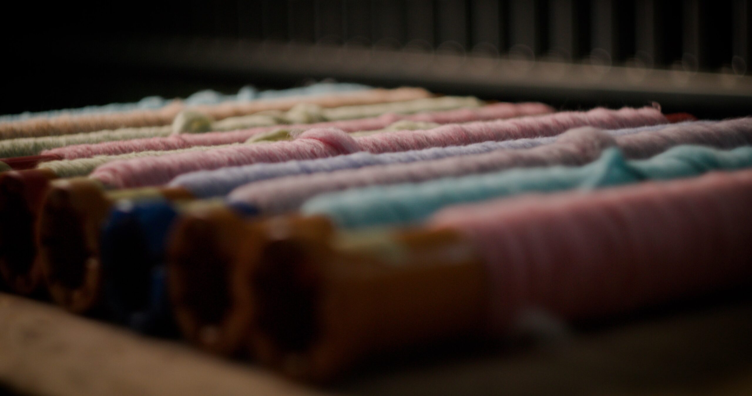 Roving, - thin slivers of fibre prepped for spinning, a range of colours lined up next to each other
